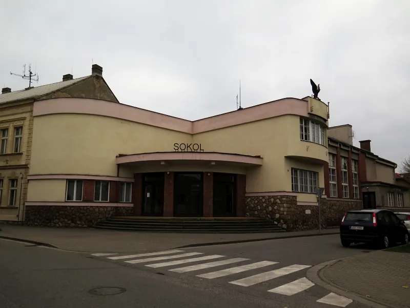 Hlavní vchod s obloukovým schodištěm a sokol na střeše